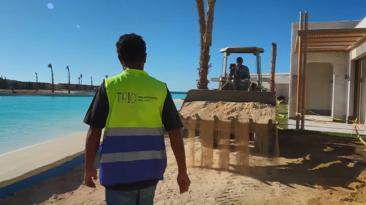 Trio Construction team member overseeing landscaping works beside the lagoon and residential chalets at The Med